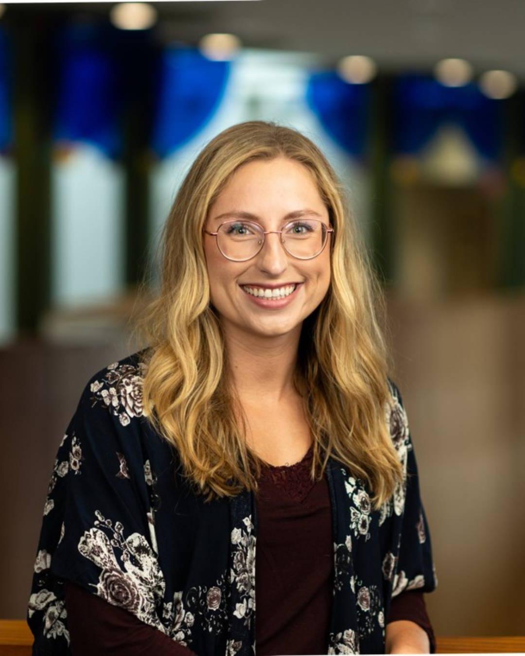 Image of a smiling woman with wavy brown hair and glasses